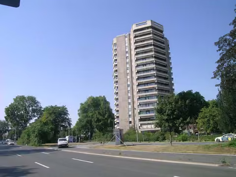 Zwangsversteigerung Eigentumswohnung in Düsseldorf, Golzheim – Vollansicht des 18-geschossigen Hochhauses vom Kennedydamm Süd.