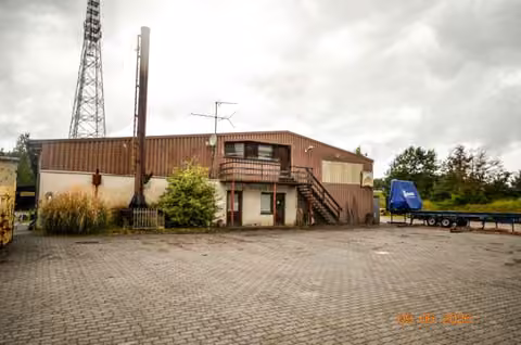 Zwangsversteigerung Grundstück in Lychen, Retzow – Außenansicht der Sägehalle mit befestigter Hoffläche und Nebengebäuden.