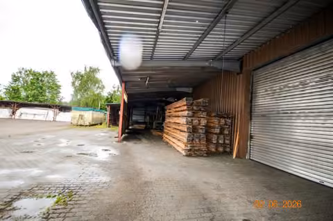Zwangsversteigerung Grundstück in Lychen, Retzow – Überdachte Produktions- bzw. Lagerhalle mit gestapeltem Schnittholz.