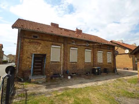 Zwangsversteigerung Zweifamilienhaus in Schipkau, Annahütte – Hofansicht auf beide Doppelhaushälften mit Eingang Nummer 64