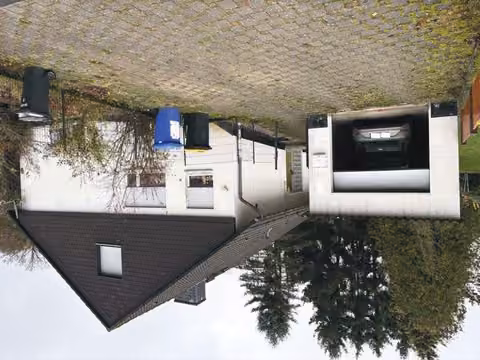 Zwangsversteigerung Einfamilienhaus in Niedenstein, Ermetheis – Frontalansicht des Einfamilienhauses mit Garage und Einfahrt.