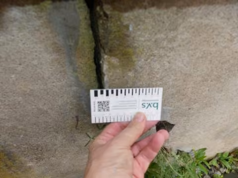 Zwangsversteigerung Einfamilienhaus in Dresden, Cossebaude – Massive Risse in der straßenseitigen Stützmauer mit Risslineal dokumentiert.