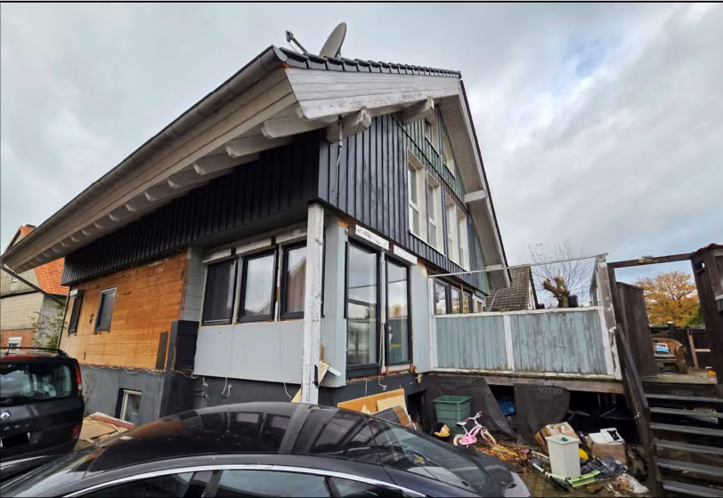 Zwangsversteigerung Einfamilienhaus in Salzhemmendorf, Ockensen – Rückansicht des Gebäudes mit hölzernem Balkon und Terrasse.