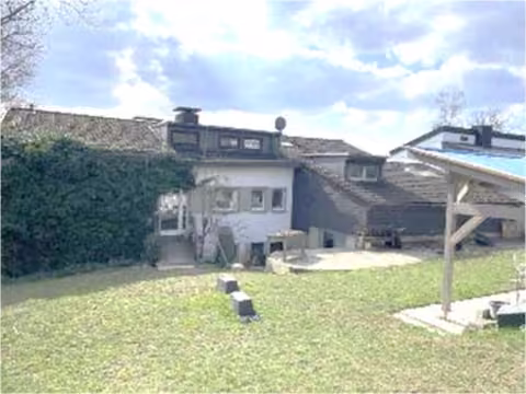 Zwangsversteigerung Einfamilienhaus in Meinerzhagen – Ostansicht des Gebäudes mit Giebelverkleidung und Schwimmbadüberdachung.