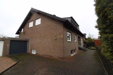 Zwangsversteigerung Mehrfamilienhaus in Ascheberg – Außenansicht des freistehenden Zweifamilienhauses mit Giebelseite und Vorgarten.