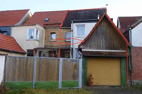 Zwangsversteigerung Doppelhaushälfte in Niedergebra – Straßenansicht der Doppelhaushälfte mit Garagentor und Anbau.