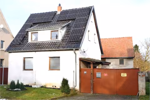 Zwangsversteigerung Einfamilienhaus in Freienbessingen – Wohnhaus Südansicht mit Giebelseite, Hofeinfahrt und PV-Modulen auf dem Dach.