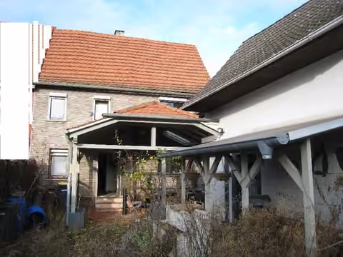 Zwangsversteigerung Doppelhaushälfte in Büdingen, Düdelsheim – Gesamtansicht beider Flurstücke mit Wohnhaus, Hofüberdachung und Garage von der Straße.