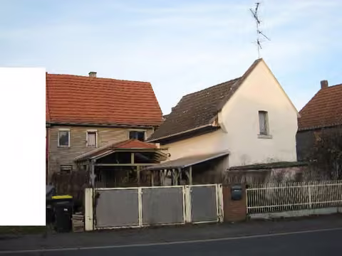 Zwangsversteigerung Doppelhaushälfte in Büdingen, Düdelsheim – Hofansicht des Wohnhauses mit südlichem Nebengebäude und Überdachung.