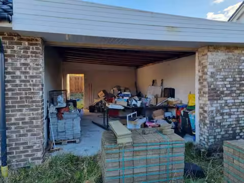 Zwangsversteigerung Einfamilienhaus in Twist, Schöninghsdorf – Blick in die unfertige Garage ohne Garagentor mit gelagertem Baumaterial.