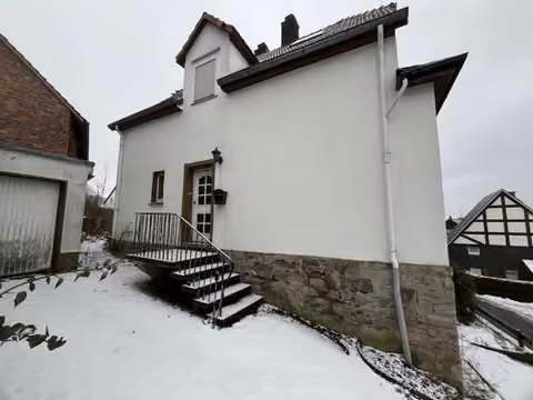 Zwangsversteigerung Einfamilienhaus in Marsberg, Padberg – Seitliche Ansicht mit Außentreppe und Hauseingangsbereich.