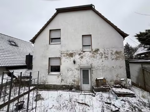 Zwangsversteigerung Einfamilienhaus in Marsberg, Padberg – Rückwärtige Gebäudeansicht mit sichtbaren Putzabplatzungen an der Fassade.