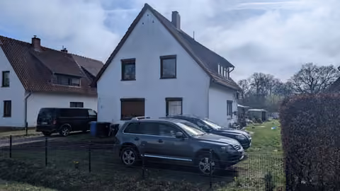 Zwangsversteigerung Einfamilienhaus in Osterholz-Scharmbeck – Seitenansicht des Wohnhauses mit Einfahrt und Nachbarbebauung.