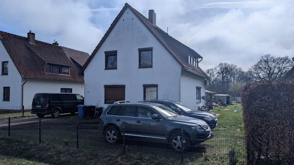 Zwangsversteigerung Einfamilienhaus in Osterholz-Scharmbeck – Seitenansicht des Wohnhauses mit Einfahrt und Nachbarbebauung.