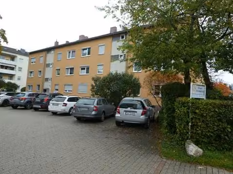 Zwangsversteigerung Eigentumswohnung in Geretsried, Gartenberg – Nordwestansicht der Wohnanlage und Parkplatzflächen vor dem Haus.
