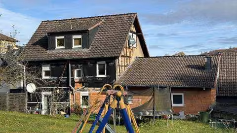 Zwangsversteigerung Einfamilienhaus in Schmitten, Arnoldshain – Gartenansicht des Wohnhauses mit Anbau und Außengelände.