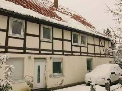 Zwangsversteigerung Zweifamilienhaus in Bad Driburg, Reelsen – Westseite mit Haupteingang und sichtbaren Feuchteschäden am Sockelputz.