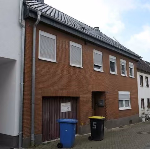 Zwangsversteigerung Reihenhaus in Kerpen, Kerpen-Stadt – Vorderansicht des verklinkerten Reihenmittelhauses mit Garagentor
