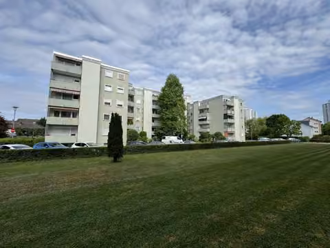Zwangsversteigerung Eigentumswohnung in Maintal, Bischofsheim – Außenansicht des Mehrfamilienhauses über die angrenzende Grünfläche.