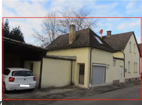 Zwangsversteigerung Einfamilienhaus in Hanau, Großauheim – Straßenansicht des bebauten Grundstücks mit Carport, Nebengebäude und Hauptgebäude.