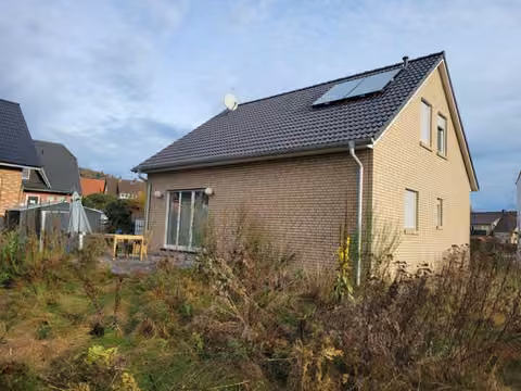 Zwangsversteigerung Einfamilienhaus in Hüllhorst, Oberbauerschaft – Nord-Westansicht mit Terrasse und Solarmodulen auf dem Dach.