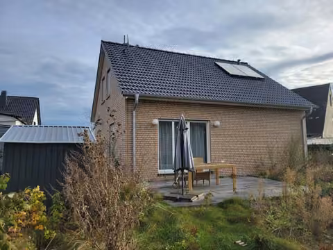 Zwangsversteigerung Einfamilienhaus in Hüllhorst, Oberbauerschaft – Süd-Westansicht mit Gartenbereich und Wildwuchs.