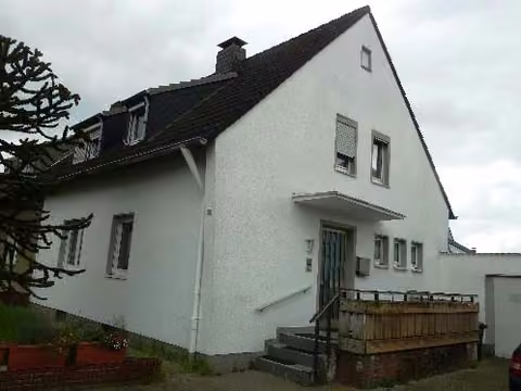 Zwangsversteigerung Zweifamilienhaus in Dormagen, Delhoven – Vorderansicht der Doppelhaushälfte mit Hauseingang und Vorgartenbereich.