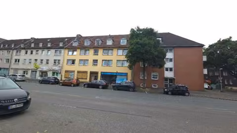 Zwangsversteigerung Eigentumswohnung in Gelsenkirchen, Schalke – Straßenseitige Gesamtansicht des dreigeschossigen Wohn- und Geschäftshauses mit Dachgeschoss.