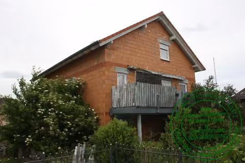 Zwangsversteigerung Einfamilienhaus in Lisberg – Außenansicht des Neubaus Kasernstraße 12a mit Balkon und unverputzter Fassade.