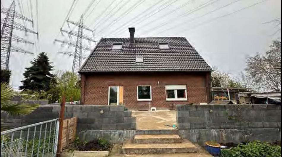 Zwangsversteigerung Einfamilienhaus in Wesel, Obrighoven – Süd-West-Ansicht mit sichtbaren Masten der Hochspannungsfreileitungen.