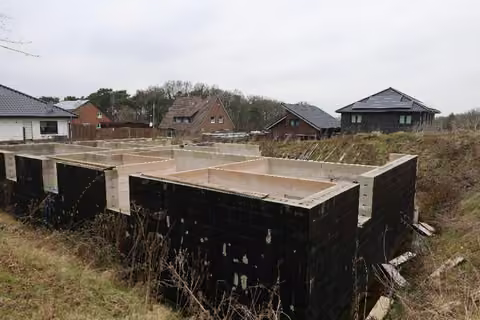 Zwangsversteigerung Zweifamilienhaus in Ibbenbüren, Bockraden – Außenansicht des Kellerrohbaus mit unvollendeten Außenwänden und Baugrube.