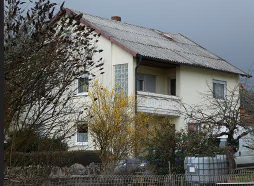 Zwangsversteigerung Einfamilienhaus in Sandberg, Langenleiten – Südostansicht des Wohnhauses mit Balkon und Hofbereich.