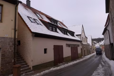 Zwangsversteigerung Stellplatz/Garage in Burghaslach – Straßenseitige Gesamtansicht des Kettenwohnhauses mit Keller- und Garagentoren von Südosten.