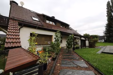 Zwangsversteigerung Einfamilienhaus in Limbach-Oberfrohna, Rußdorf – Südansicht des Hauses mit gepflegtem Zugang und Bepflanzung.