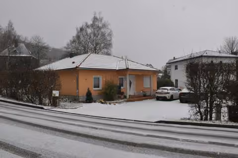 Zwangsversteigerung Einfamilienhaus in Zwickau, Auerbach – Nordwestansicht des Einfamilienhauses mit Grundstückszufahrt und Eingangsbereich im Winter.