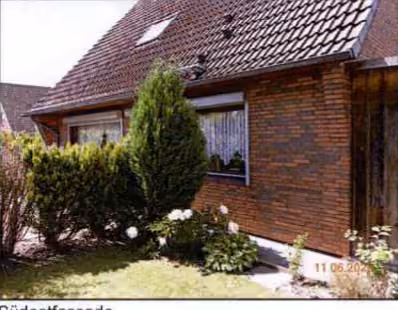 Zwangsversteigerung Einfamilienhaus in Brunsbüttel – Gartenansicht des Einfamilienhauses mit Heckenbegrenzung