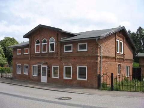 Zwangsversteigerung Mehrfamilienhaus in Schönwalde am Bungsberg – Straßenseitige Ansicht des Zweifamilienhauses mit Backsteinfassade und Krüppelwalmdach.