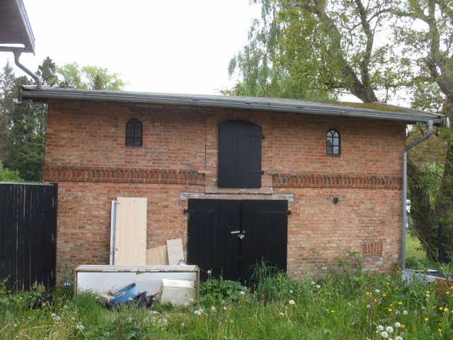 Zwangsversteigerung Mehrfamilienhaus in Schönwalde am Bungsberg – Südansicht des Wohnhauses mit Flachdachanbau und Gartenseite.