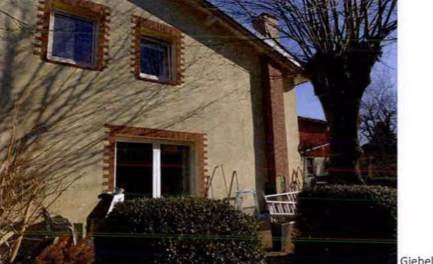 Zwangsversteigerung Gewerbe in Hadenfeld – Giebelansicht des Wohnhauses mit Terrasse und Gartenbereich.