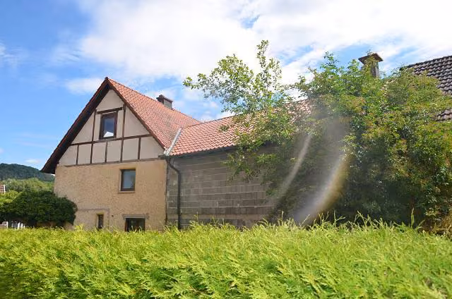Zwangsversteigerung Zweifamilienhaus in Grabfeld, Wölfershausen – Straßenansicht des massiven Scheunengebäudes mit Holzgiebel und Garagentoren.