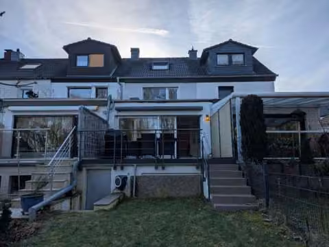 Zwangsversteigerung Reihenhaus in Dortmund, Kley – Gartenseitige Ansicht des Gebäudes mit Anbau und Terrasse.