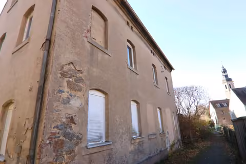 Zwangsversteigerung Einfamilienhaus in Zittau, Hirschfelde – Straßenseitige Fassade mit Putzschäden entlang des schmalen Gehwegs.