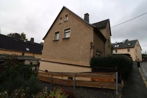 Zwangsversteigerung Zweifamilienhaus in Wilkau-Haßlau – Nord-West-Giebelansicht des Gebäudes mit Grundstückseinfriedung.