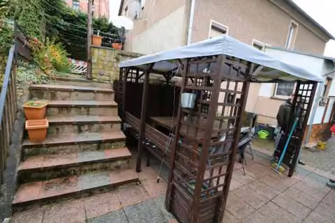 Zwangsversteigerung Zweifamilienhaus in Wilkau-Haßlau – Gestalteter Außensitzplatz mit Pavillon und Treppenaufgang im Garten.
