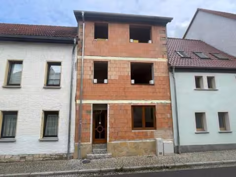 Zwangsversteigerung Einfamilienhaus in Bad Sulza – Straßenseitige West-Ansicht des Reihenmittelhauses im Rohbauzustand.
