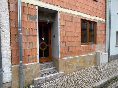 Zwangsversteigerung Einfamilienhaus in Bad Sulza – Detailansicht des Hauseingangs im Erdgeschoss mit Natursteinsockel.