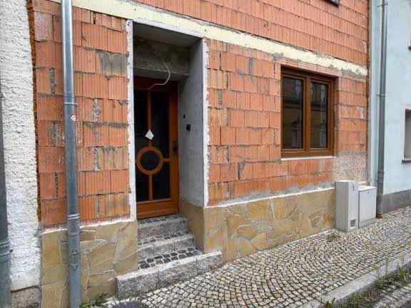 Zwangsversteigerung Einfamilienhaus in Bad Sulza – Detailansicht des Hauseingangs im Erdgeschoss mit Natursteinsockel.