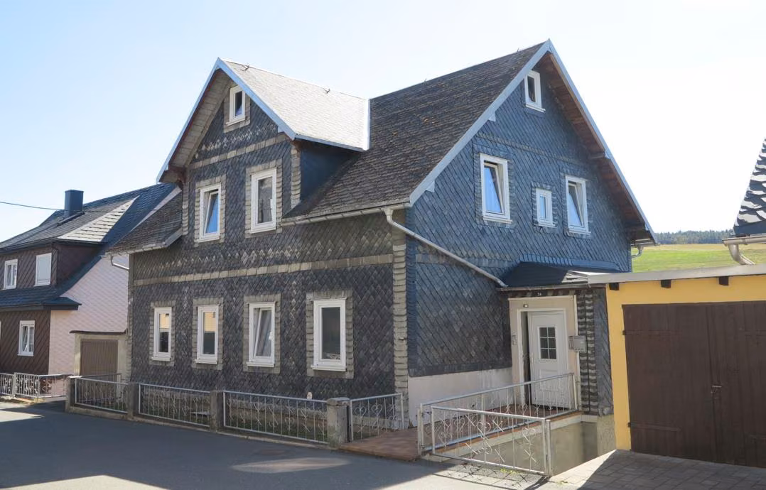Zwangsversteigerung Einfamilienhaus in Neuhaus am Rennweg, Piesau – Giebelseite des Wohnhauses mit Schieferverkleidung.