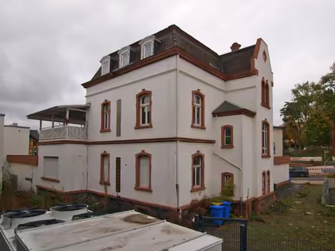 Zwangsversteigerung in Homberg (Efze) – Rückwärtige Gebäudeansicht des Wohnhauses von Süden mit Anbau und Dachterrasse.