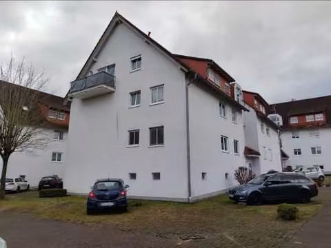 Zwangsversteigerung Eigentumswohnung in Brachttal, Neuenschmidten – Außenansicht des Mehrfamilienhauses von Nordosten mit Kennzeichnung der Dachgeschosswohnung.